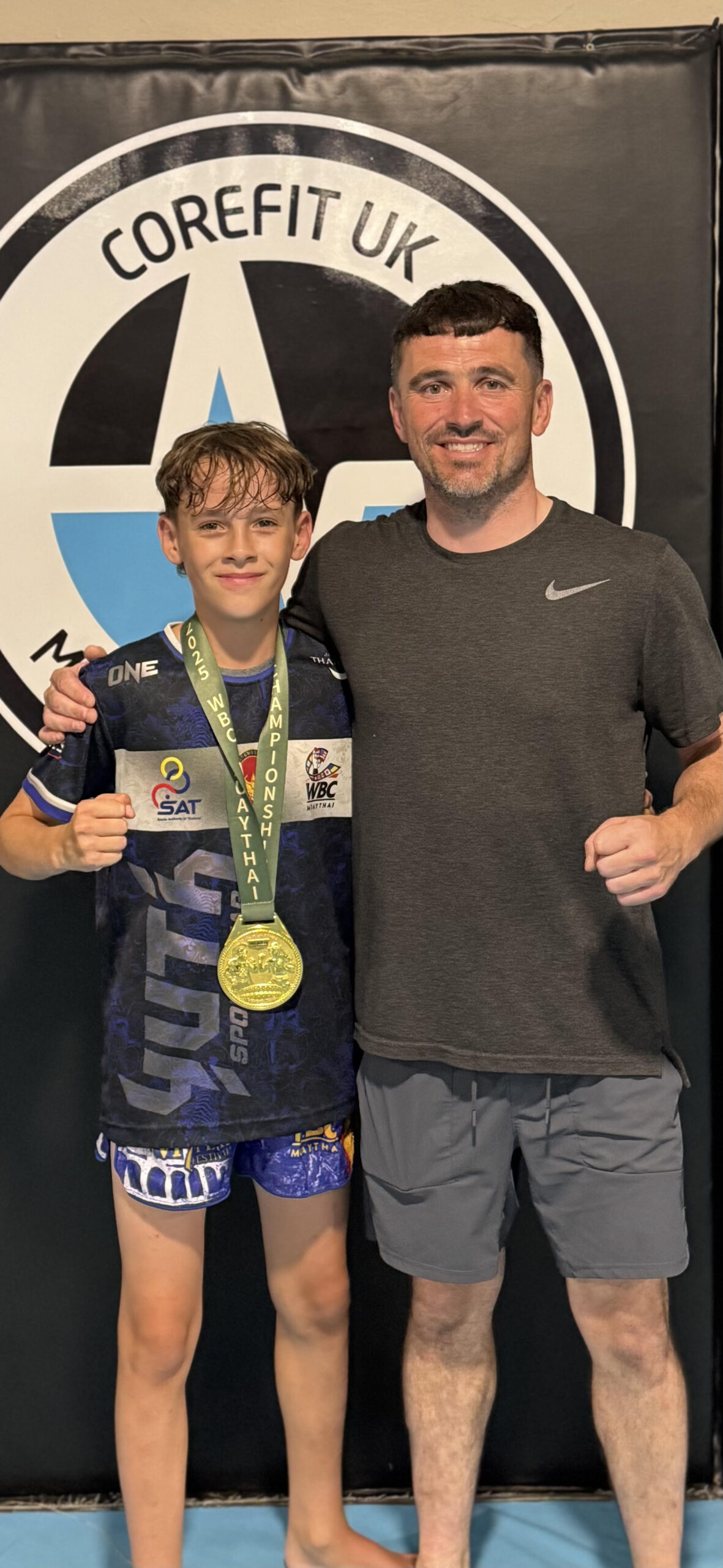 Travis Abercrombie and Coach Henry Cleminson celebrating with WBC Muay Thai Gold Medal at Corefit UK